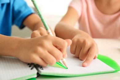 Photo of Little boy and girl doing homework at table indoors, closeup