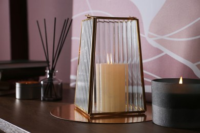 Photo of Stylish glass holder with candle and decor on wooden table indoors
