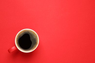 Photo of Cup of aromatic coffee on red background, top view. Space for text