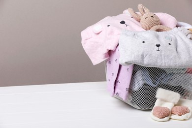 Photo of Laundry basket with baby clothes on white wooden table, space for text