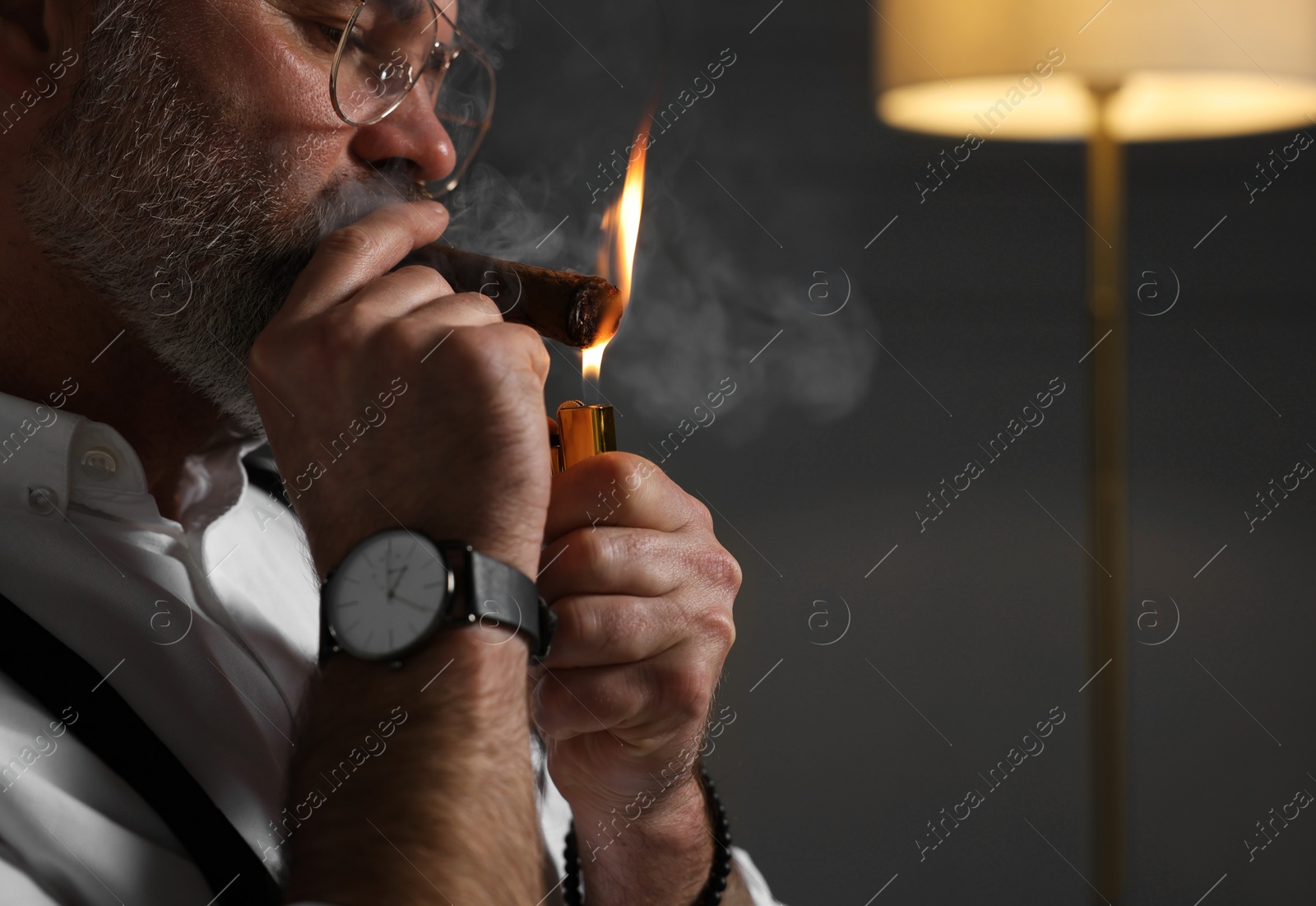 Photo of Bearded man lighting cigar indoors, closeup. Space for text