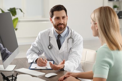 Doctor consulting patient at wooden table in clinic