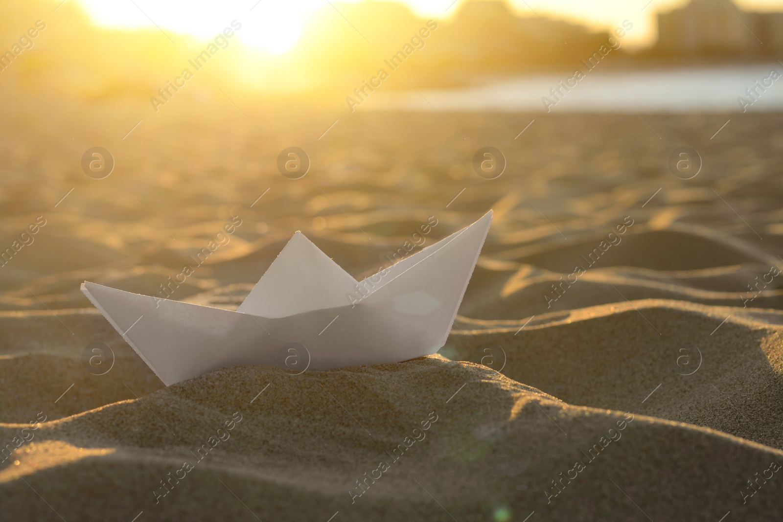 Photo of Beautiful white paper boat on sand outdoors, closeup