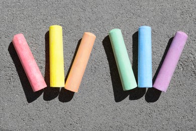 Photo of Colorful chalk sticks on asphalt outdoors, flat lay