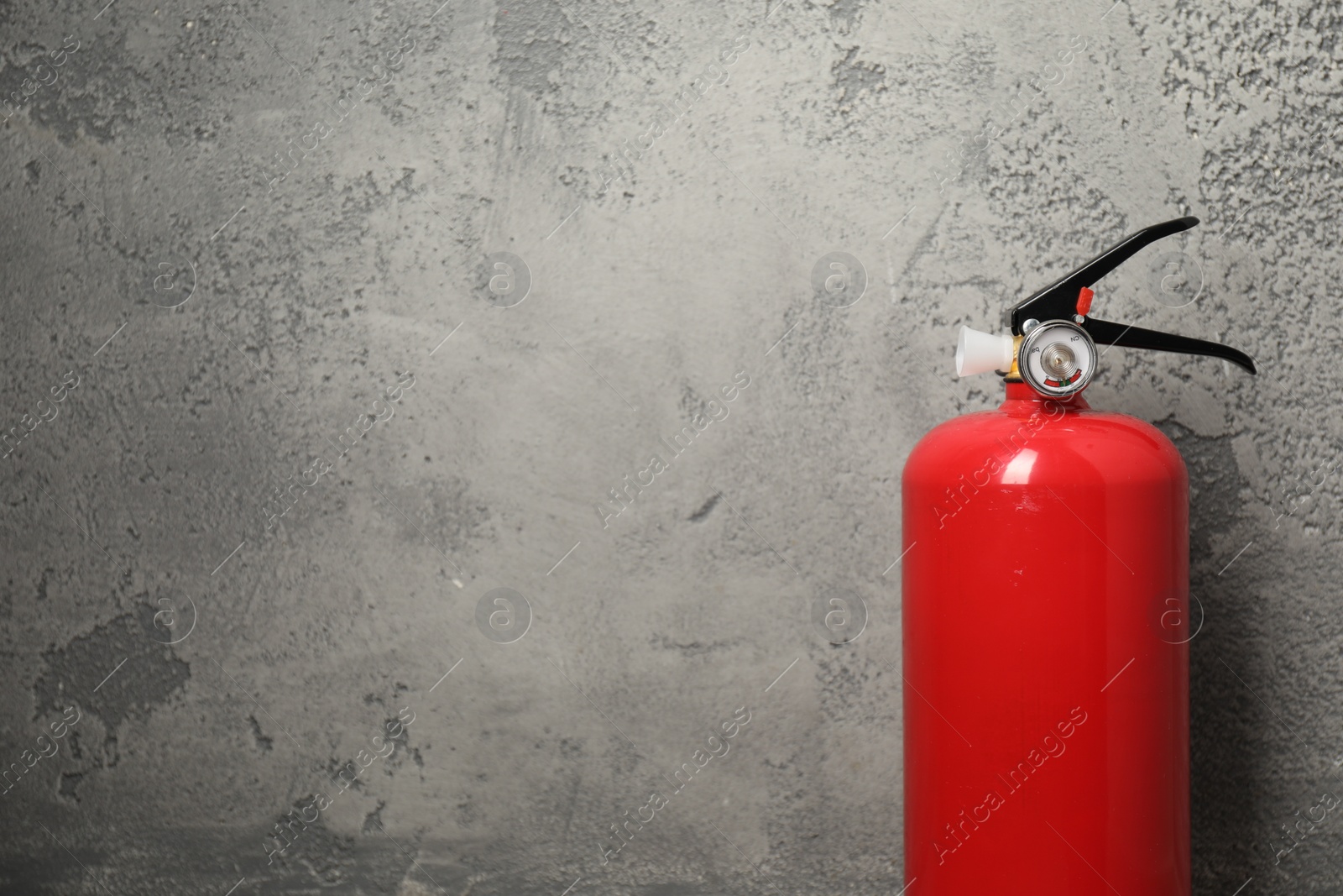 Photo of Fire extinguisher on grey textured background, space for text