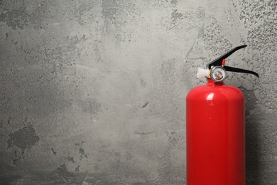 Photo of Fire extinguisher on grey textured background, space for text