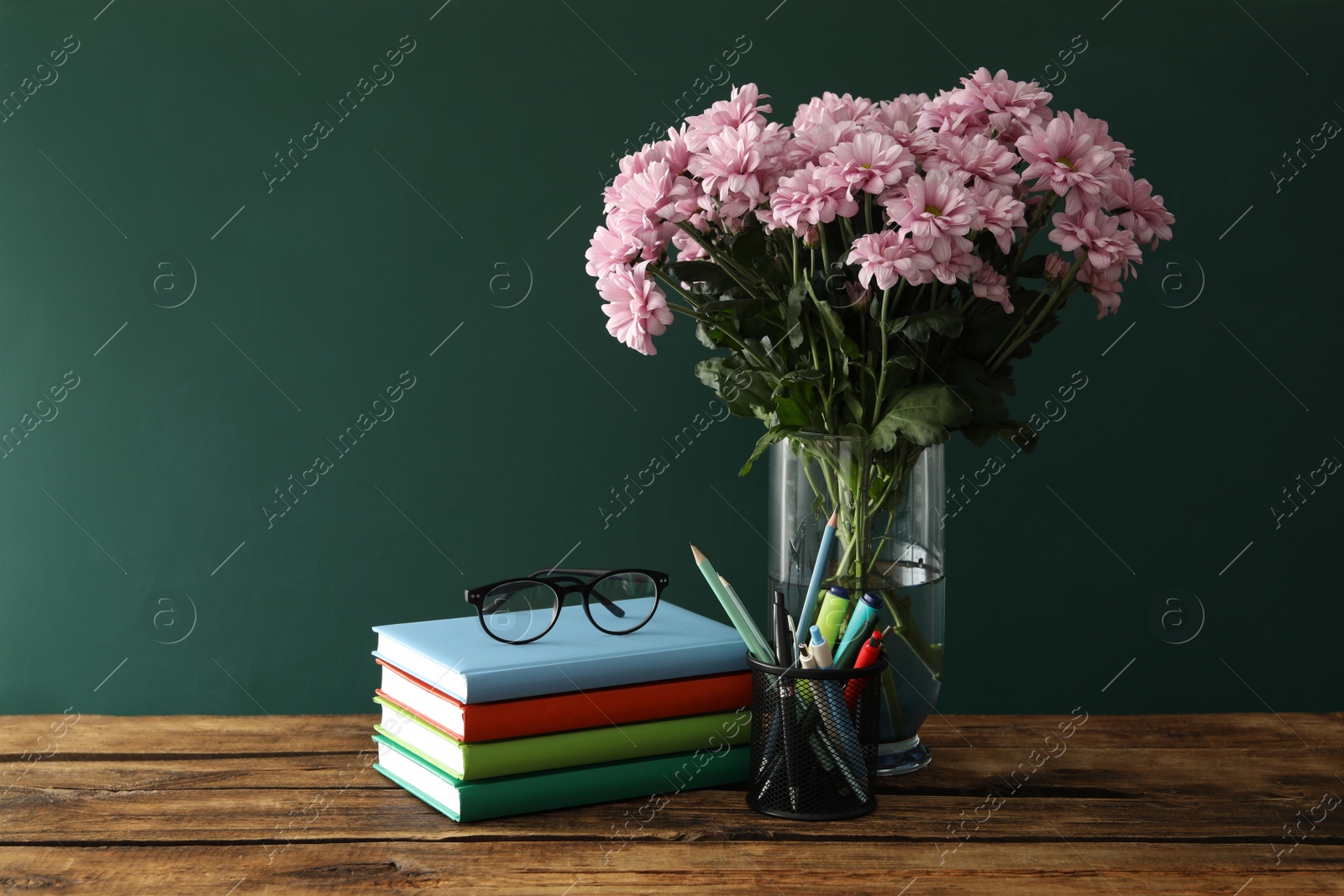 Photo of Set of stationery and flowers on wooden table near chalkboard. Teacher's Day