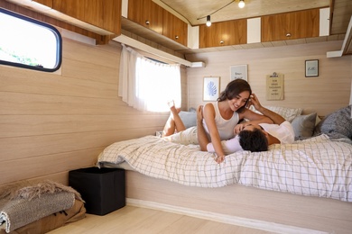 Photo of Happy young couple on bed in trailer. Camping vacation