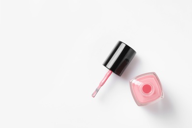 Bottle of color nail polish with brush on white background, top view