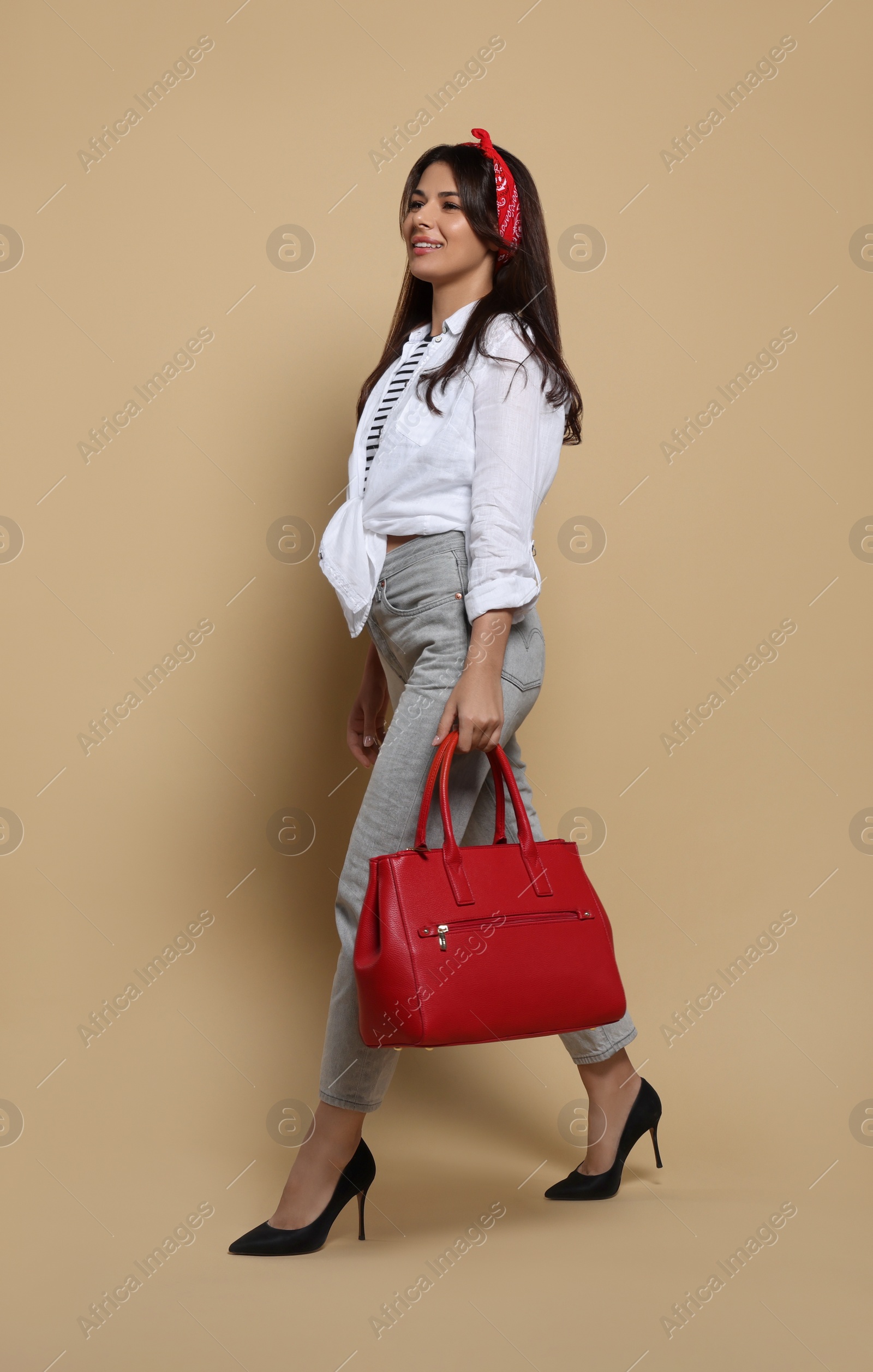 Photo of Young woman with stylish bag on beige background