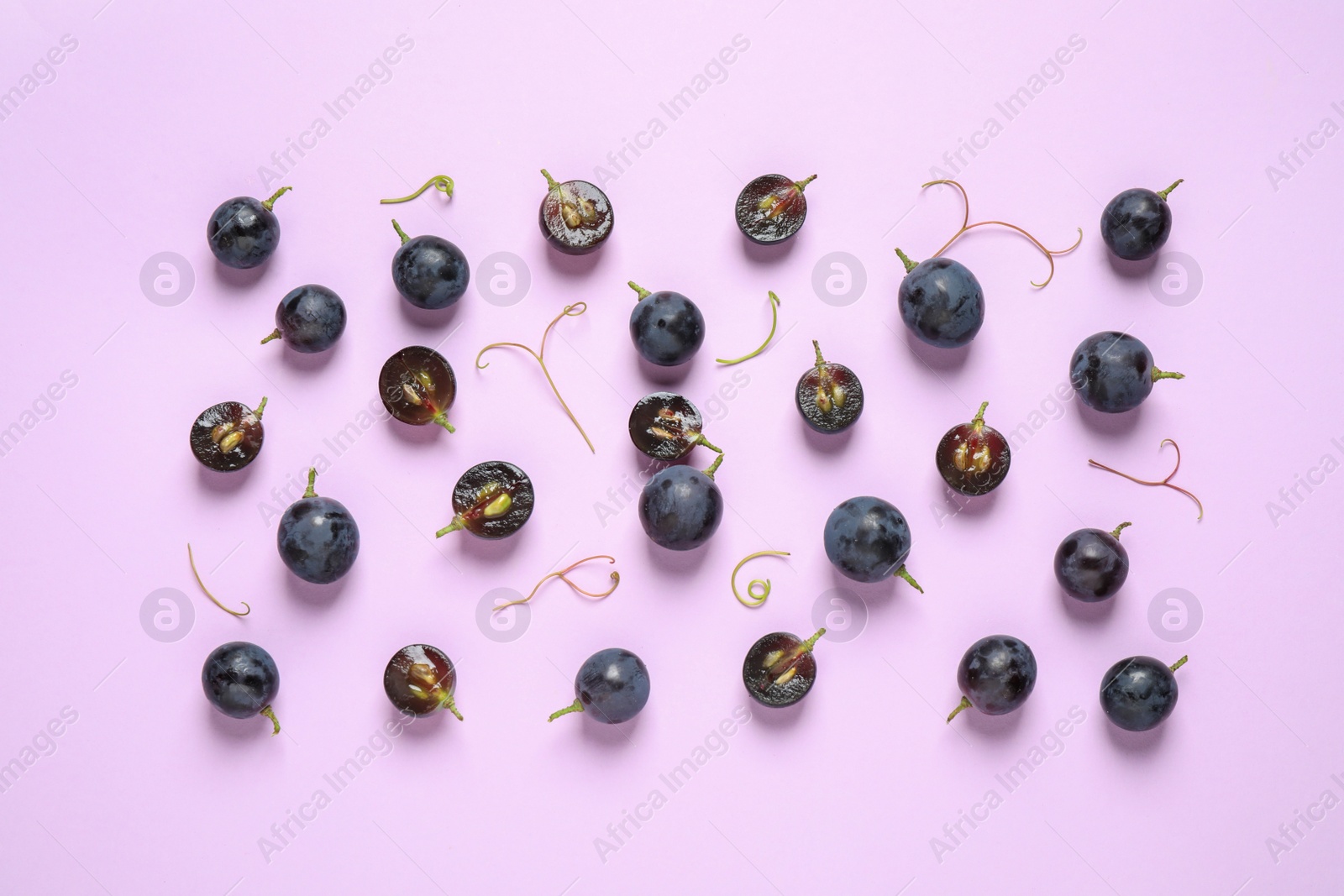 Photo of Flat lay composition with fresh ripe juicy grapes on lilac background