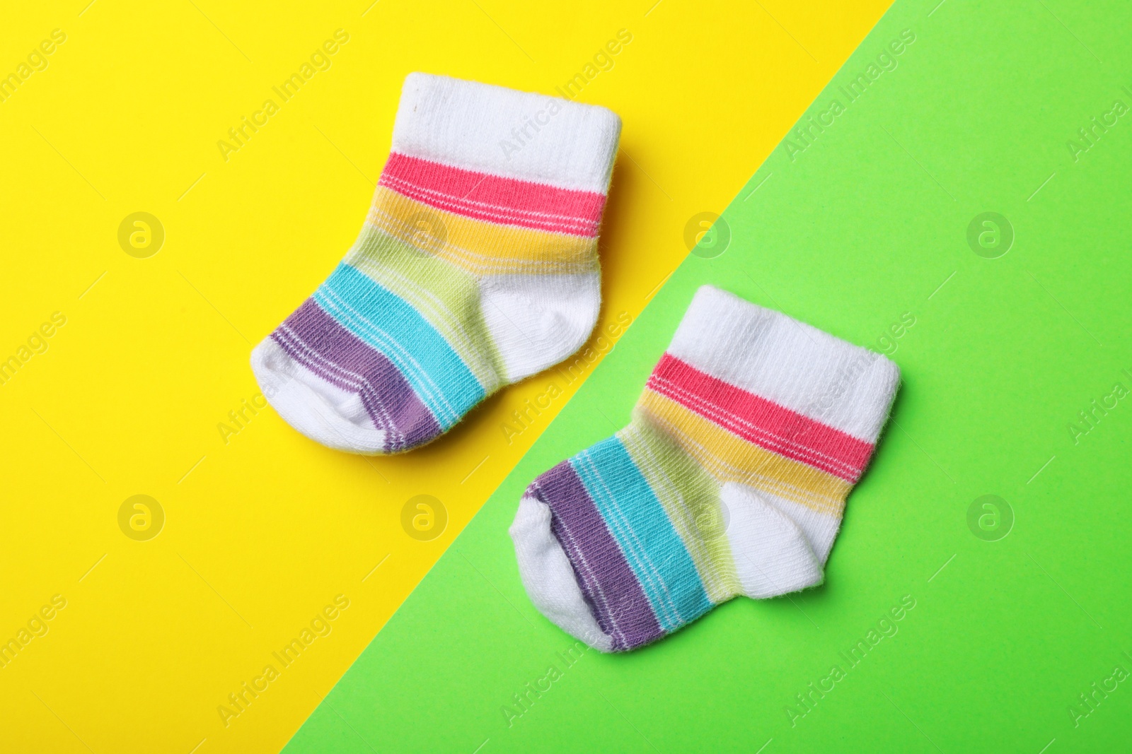 Photo of Pair of cute child socks on color background, top view