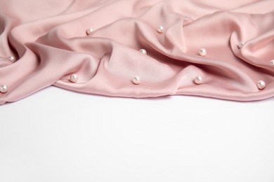 Texture of delicate pink silk with pearls on white background