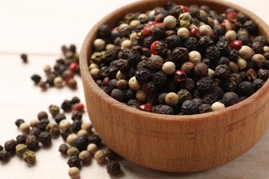 Photo of Aromatic spices. Different peppers in wooden bowl on table, closeup