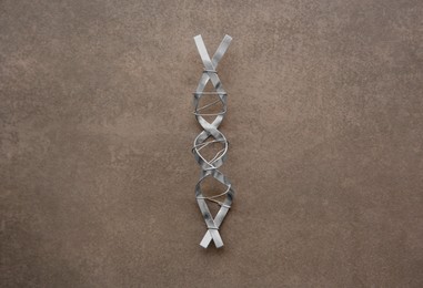 Photo of DNA molecule model made of metal on brown background, top view