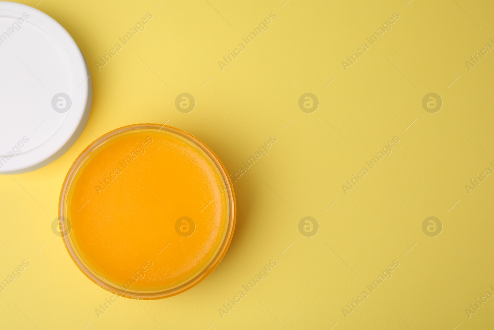 Photo of Open jar of petrolatum on yellow background, top view. Space for text