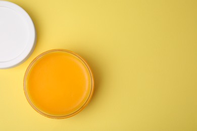 Photo of Open jar of petrolatum on yellow background, top view. Space for text