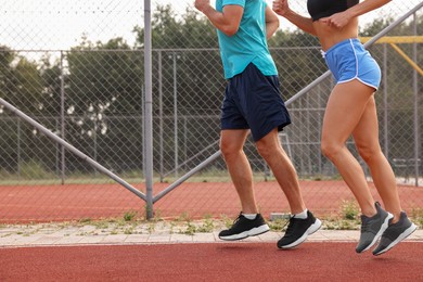 Healthy lifestyle. Sporty couple running at stadium, closeup with space for text