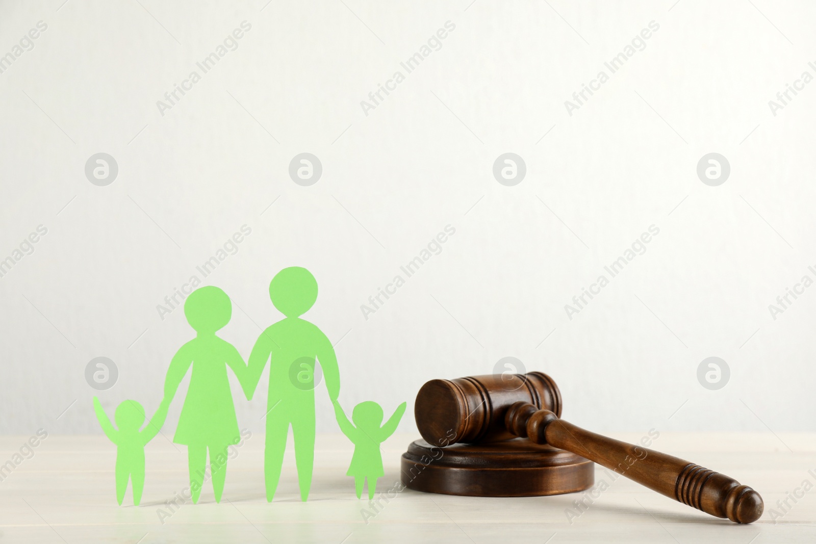 Photo of Paper family figure and wooden gavel on white table. Child adoption concept