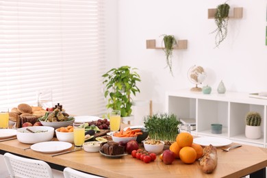 Healthy vegetarian food, glasses of juice, cutlery and plates on wooden table indoors