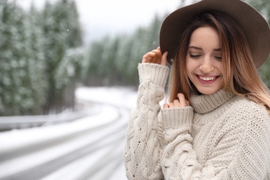 Photo of Young woman in warm sweater outdoors, space for text. Winter vacation