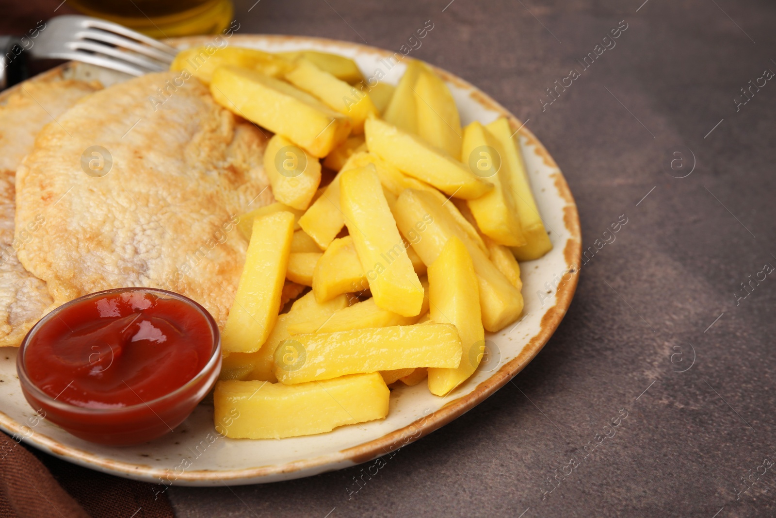 Photo of Delicious fish and chips with ketchup served on brown table, closeup