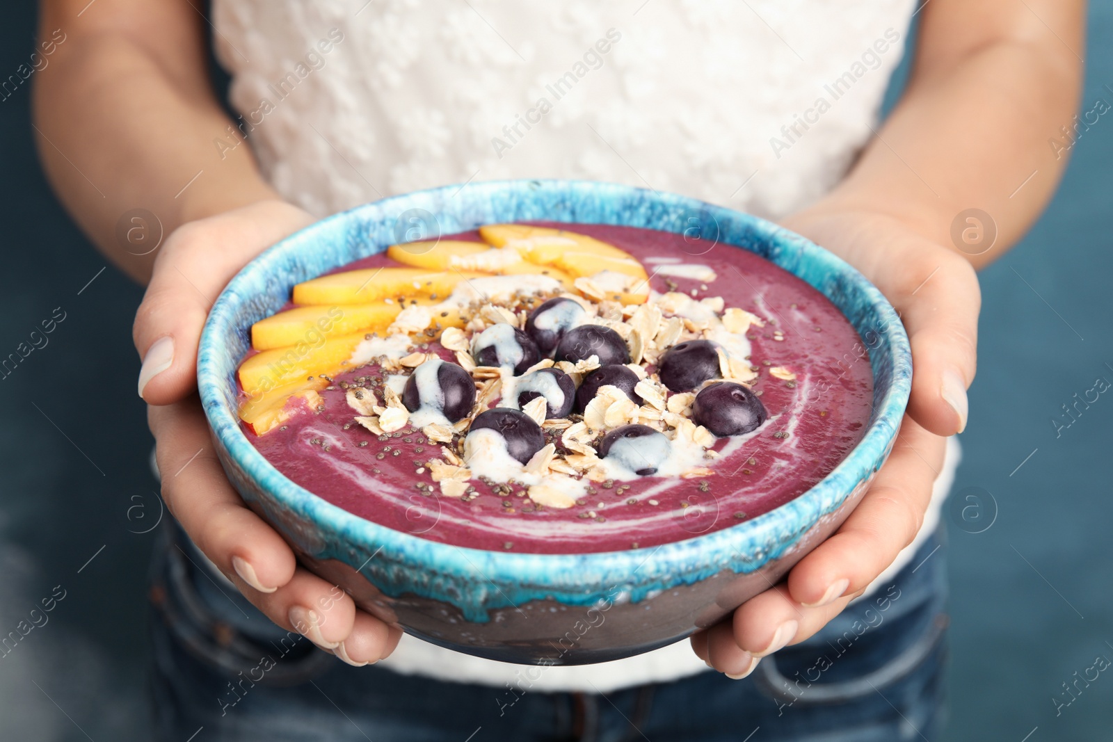 Photo of Woman holding bowl with tasty acai smoothie, closeup