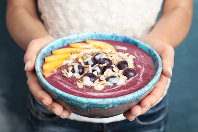 Photo of Woman holding bowl with tasty acai smoothie, closeup