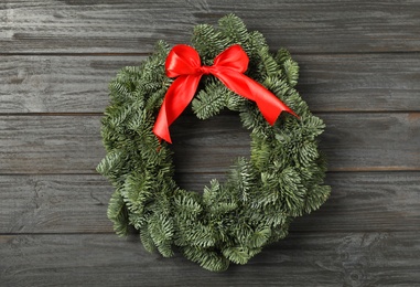 Christmas wreath made of fir tree branches with red ribbon on black wooden background