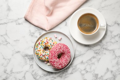 Yummy donuts with sprinkles and coffee on white marble table, flat lay
