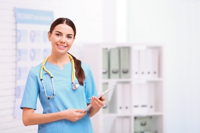 Photo of Portrait of medical assistant with stethoscope and tablet in hospital. Space for text