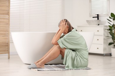 Photo of Menopause. Depressed woman near bath tub in bathroom