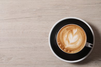 Photo of Cup of aromatic coffee on wooden table, top view. Space for text