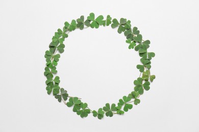 Photo of Frame of green clover leaves on white background, flat lay. Space for text