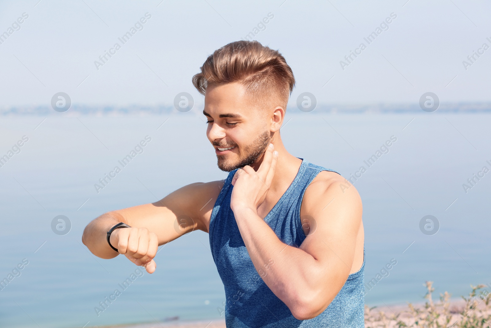 Photo of Young man checking pulse outdoors on sunny day