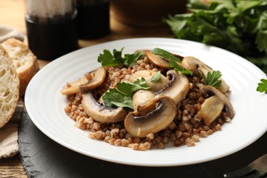 Tasty buckwheat with fresh parsley and mushrooms on table, closeup