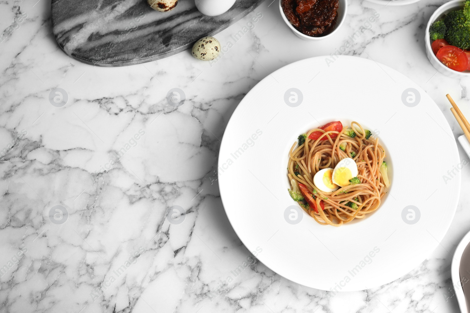 Photo of Tasty buckwheat noodles served on white marble table, flat lay. Space for text