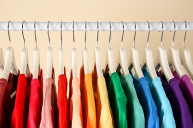 Photo of Many t-shirts hanging in order of rainbow colors, closeup