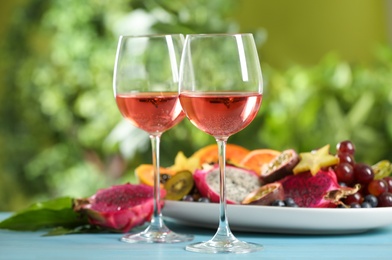 Delicious exotic fruits and wine on light blue wooden table