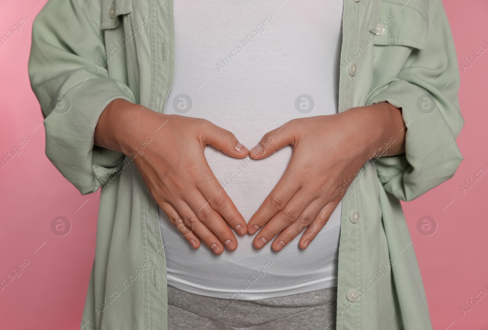 Photo of Pregnant woman on pink background, closeup view