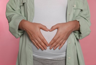 Pregnant woman on pink background, closeup view