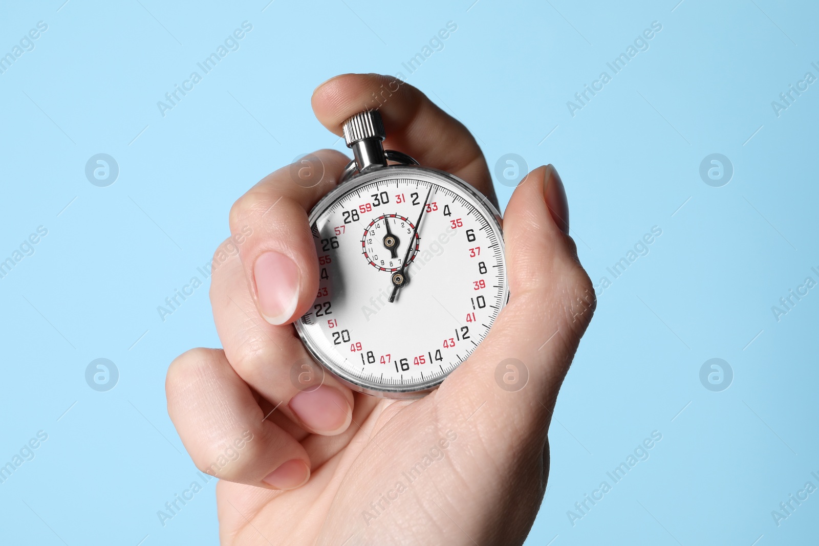 Photo of Woman holding vintage timer on light blue background, closeup