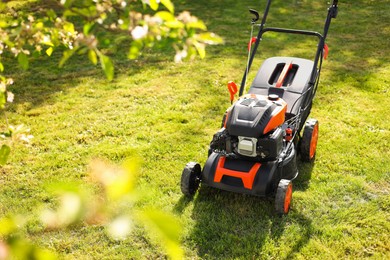 Photo of Modern lawn mower on green grass in garden