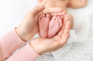 Photo of Mother holding little baby feet in hands