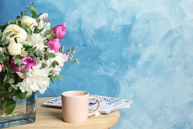 Vase with bouquet of beautiful flowers and cup on table