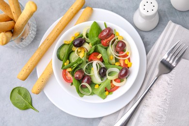 Tasty salad with leek and olives served with grissini on grey table, flat lay