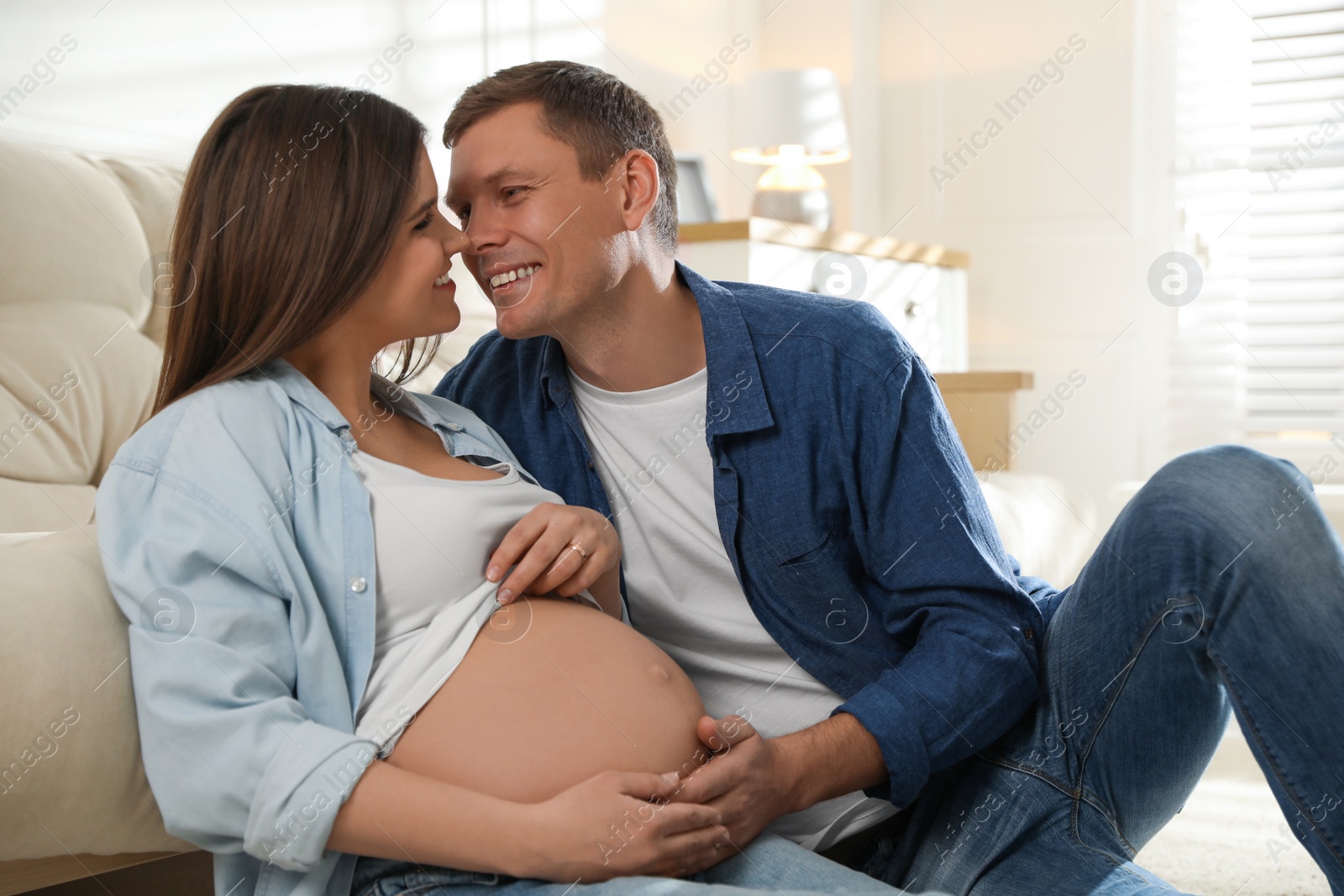 Photo of Young pregnant woman with her husband at home