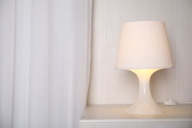 Stylish lamp on bedside table in room, space for text