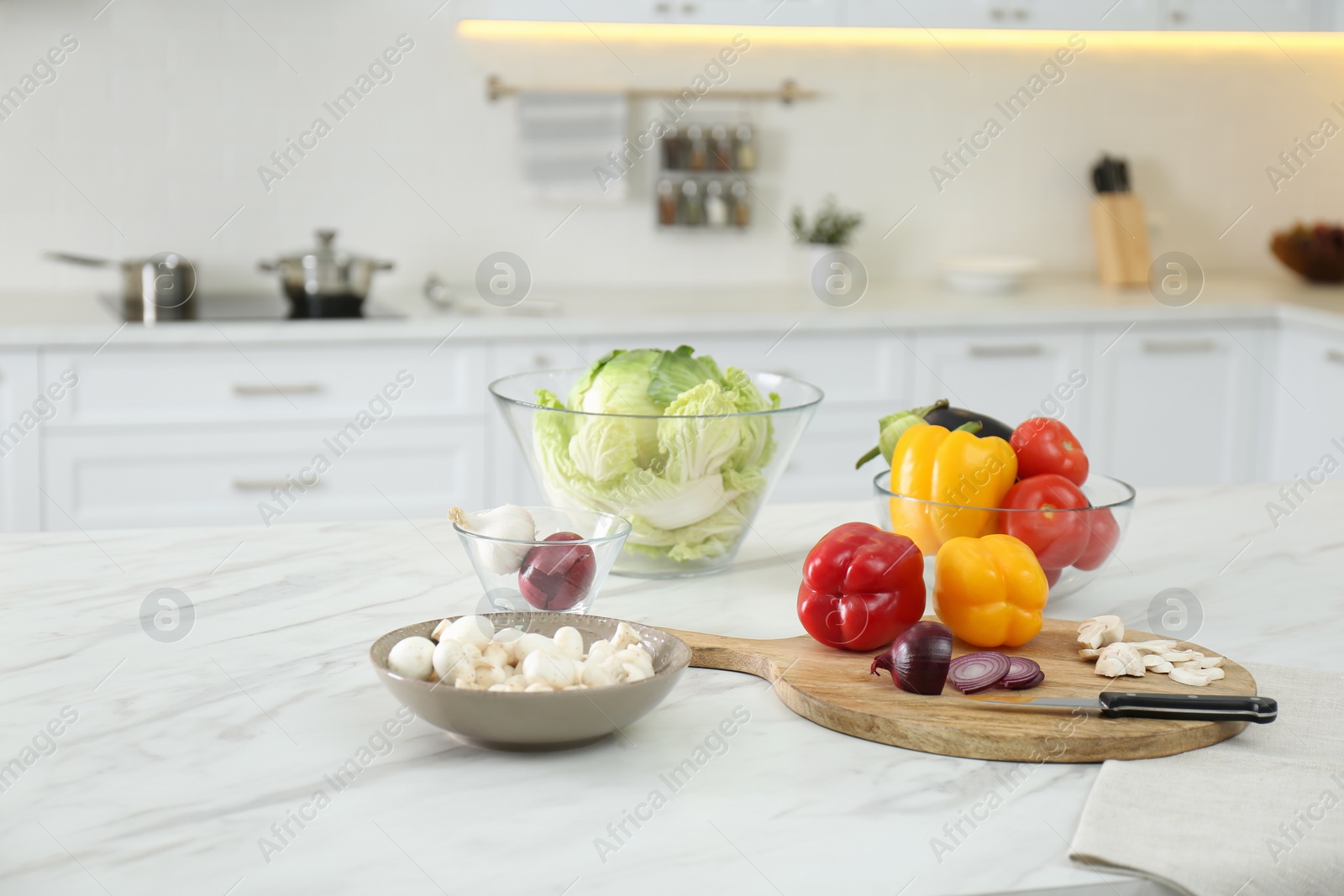 Photo of Different fresh vegetables and mushrooms on white table in modern kitchen