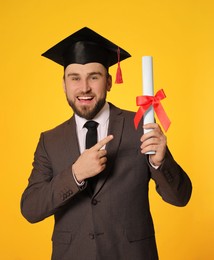 Photo of Happy student with graduation hat and diploma on yellow background